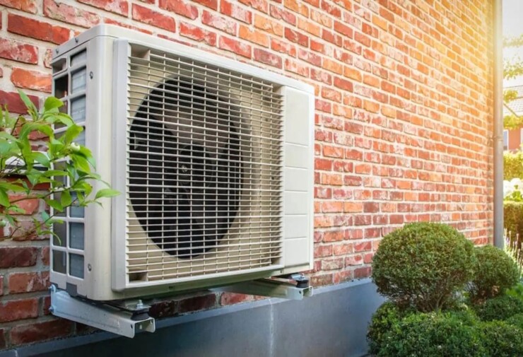 Unité extérieure de système de climatisation split fixée sur un mur en brique, installée sur support métallique, illustrant une solution de climatisation résidentielle performante pour maison individuelle.